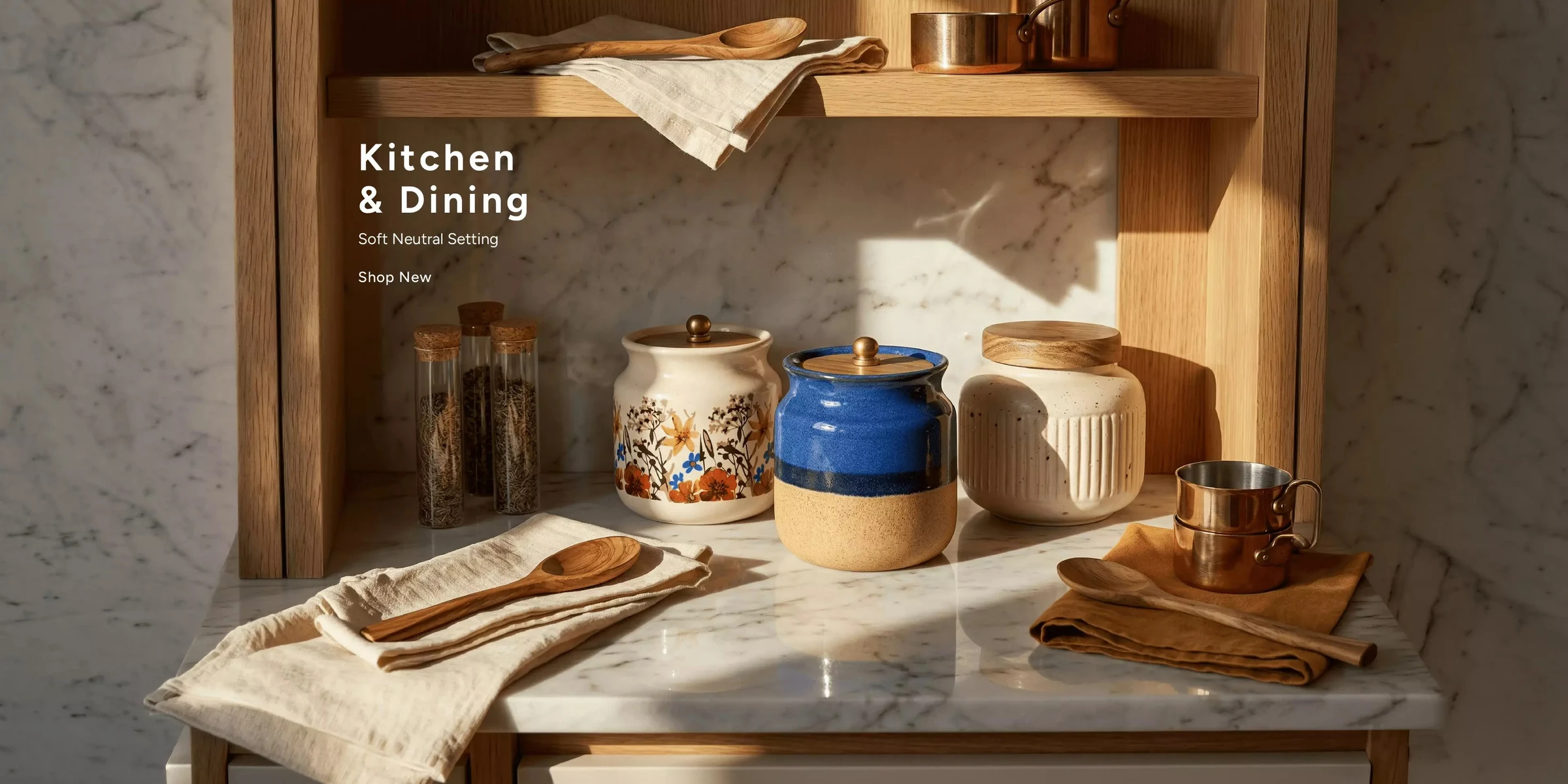 Kitchen & Dining. A soft neutral setting — ceramic storage jars, wooden servers and copper measures on a marble counter. Shop home.